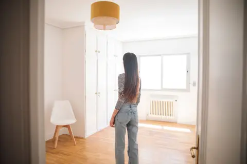 Getty Images Young woman in an empty apartment looking around - stock photo