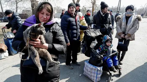 Reuters Evacuees wait for a bus before leaving Mariupol, 24 March 2022