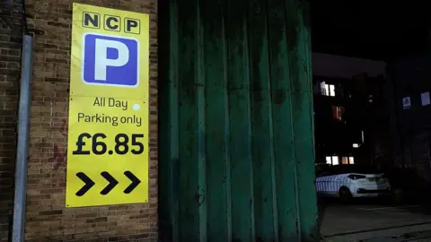 NurPhoto via Getty Images A yellow NCP sign saying "All Day Parking only £6.85"
