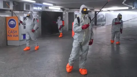 Getty Images Polish workers disinfecting a car park