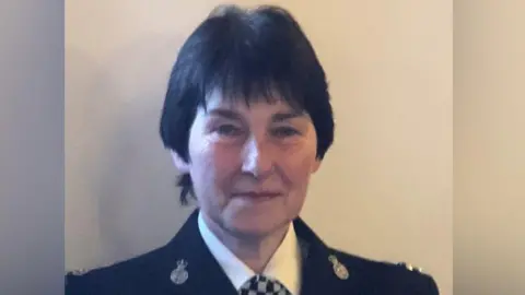 Cumbria Constabulary Susan Holliday with short black hair, wearing a black police uniform. 