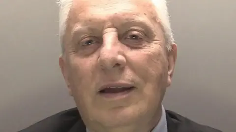 Merseyside Police A police custody photograph of Glyn Jones who has grey hair and is wearing a dark suit and light shirt.