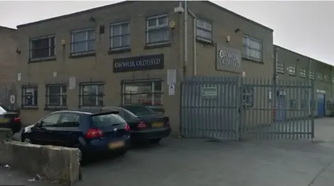 Google Two-storey brick built building with bars on windows and a large metal gate to one side