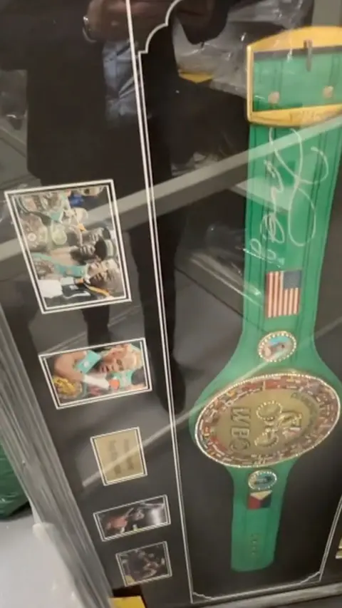 A large belt with a gold detail in the middle, in a big frame with photos.
