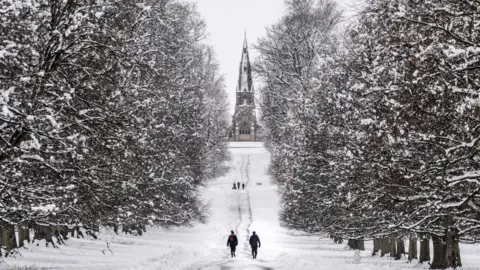 PA Media People walking in the snow in Studley Royal park in North Yorkshire.