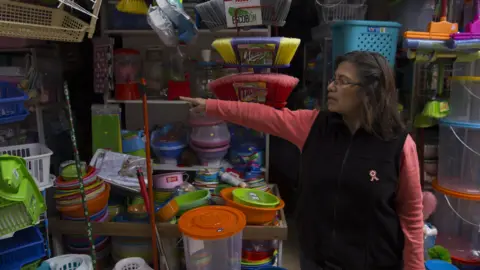 Peruvian stallholder Alejandrina Bardales points to a nearby stall in a market in Lima