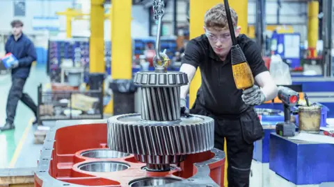 An apprentice engineer assembling a gearbox in an Engineering factory. 