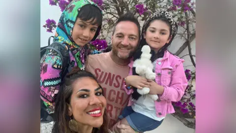 Raina Heverin A family of four smiling together.