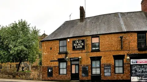 West Northamptonshire Council Brick-built two-storey pub building with Old Black Lion sign