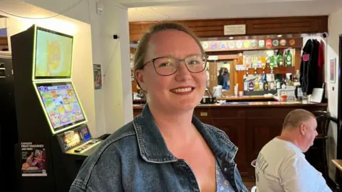 Zulekah Hattersley smiling in the main room of the Old Mill Club.
