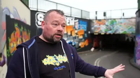 Steven O'Hara in front of a graffiti wall