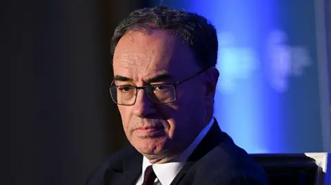 Andrew Bailey head and shoulders wearing a suit and tie with his eyes cast downwards and a serious expression on his face
