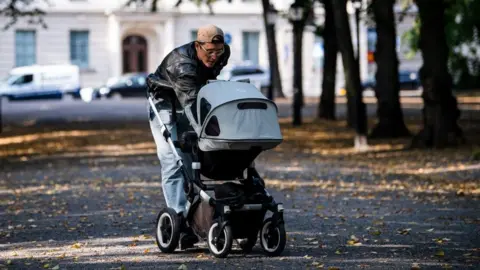 AFP A man walks his baby in a baby stroller at Humlegarden in Stockholm on 24 September 2020.