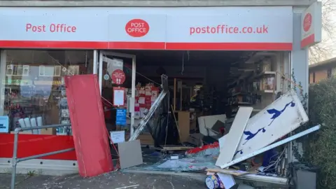 The front of a ram raided post office in Winterbourne showing the front right of the shop totally destroyed with smashed glass and debris on the floor.