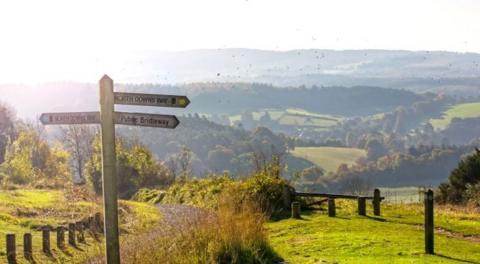 A footpath sign on the North Downs Way, with rolling hills in the background