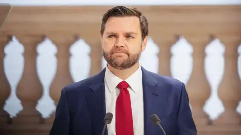 Bloomberg/Getty Images US Vice President JD Vance shown speaking at the AI Action Summit, wearing a navy suit and red tie.