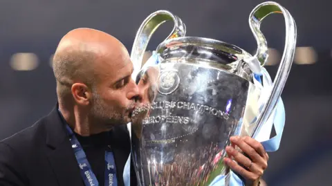 Pep Guardiola, manager of Manchester City, kisses the UEFA Champions League trophy after his team's victory.