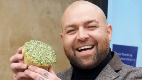 A man holding a pie next to his head