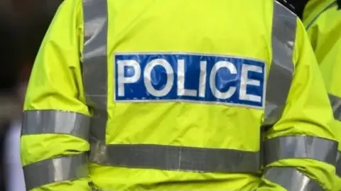 The back of a police officer wearing a high visibility jacket with "police" written on it