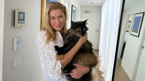 AP Margo Neas holds her cat Mittens in corridor of her home in Melbourne. Photo: 22 January 2025