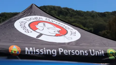 Australian Broadcasting Corporation The top of a black tent reads "Missing Persons Unit"