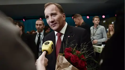 Reuters Swedish PM Stefan Lofven talks to the press, carrying red roses, after a TV debate on 7 September 2018
