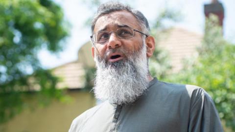 Anjem Choudary, a bearded man wearing a grey tunic, speaks
