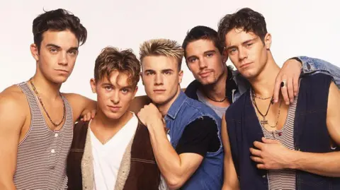 Take That pose in vests and denim shirts for an early publicity photo