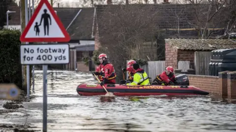 PA Media Rescue workers travelling by boat in East Cowick, Yorkshire