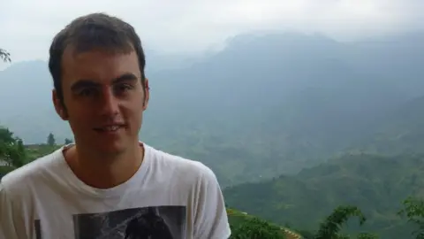 Jon travelling in Vietnam in front of misty mountains