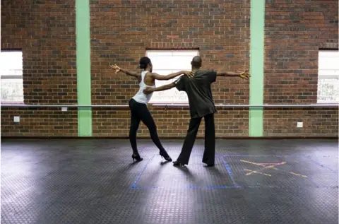 AFP Two people in a dancehall doing ballroom dancing.