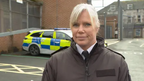 Cheif Inspector Miranda Pusey of Devon and Cornwall Police standing in front of a police car in the car park of Torquay Police station