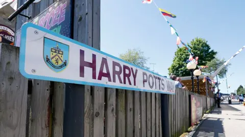 PA Media Close-up view of the claret and blue Harry Potts Way street sign in Burnley.
