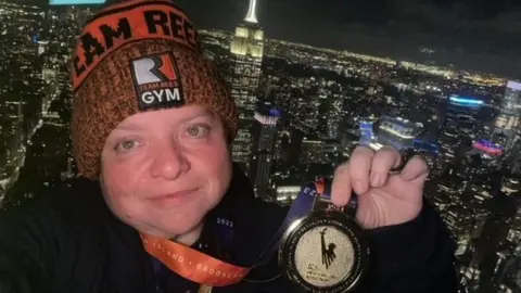 Kerrie Aldridge Kerrie Aldridge posing with medal with New York skyline in background