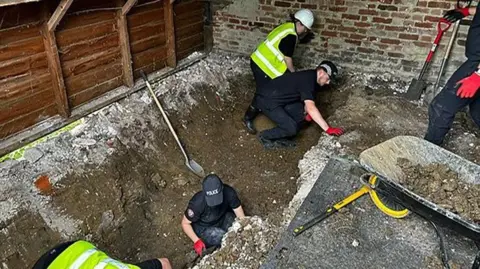 Officers digging a trench inside a barn