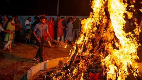 Getty Images Devotees gather around a ceremonial bonfire during Holika Dahan, marking the victory of good over evil on the eve of Holi. 