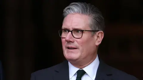 Sir Keir Starmer in dark rimmed glasses, against a black background