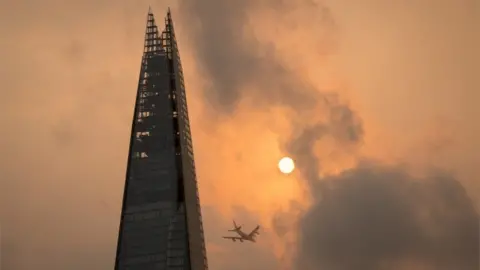 PA/Dominic Lipinski A plane flies past the Shard in central London, as the sky takes on an unusual orange colour