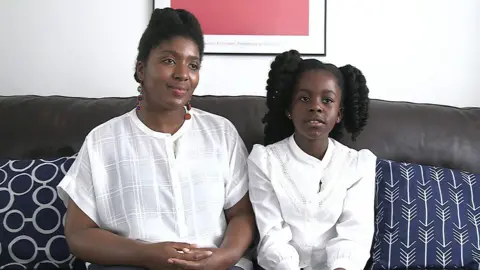 Yvonne (L) and Alyssa (R) sit on a sofa