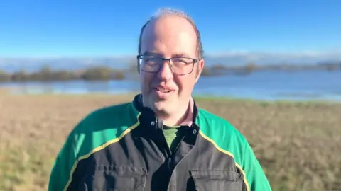 BBC A farmer in a flooded field