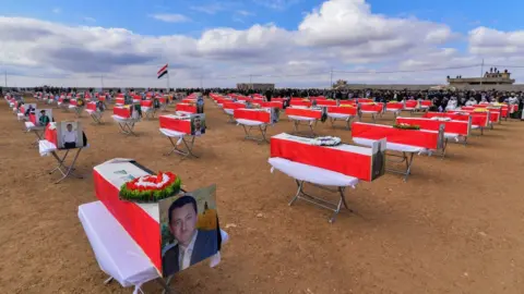 Getty Images Coffins are spaced out at the mass funeral in Kocho on 6 February 2021