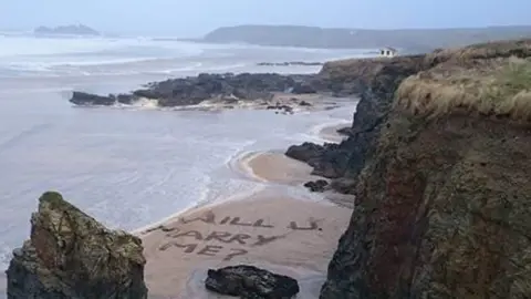 Gaynor Pinnell "Will you marry me?" written in the sand