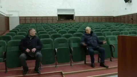 Getty Images Russia's President Vladimir Putin (R) speaks with Deputy Prime Minister Marat Khusnullin while they sit in The Mariupol Philarmonic Theatre