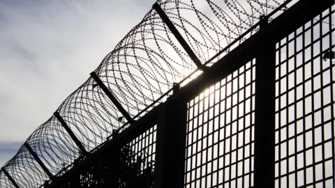 Getty Images Stock image of barbed wire on top of a fence