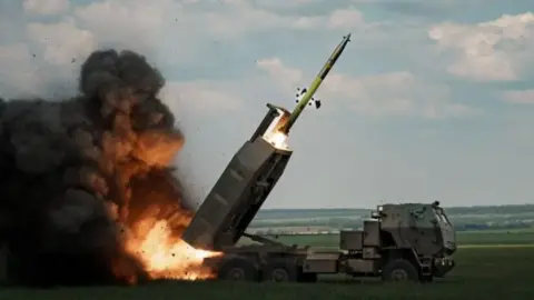 Getty Images Image of High Mobility Artillery Rocket Systems (Himars) being fired from a rural area in the background.