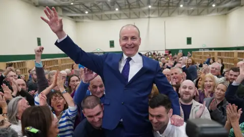 PA Media Fianna Fáil leader Micheál Martin is hoisted up by his sons Cillian and Micheal Aodh, after he was deemed elected in the Cork South Central