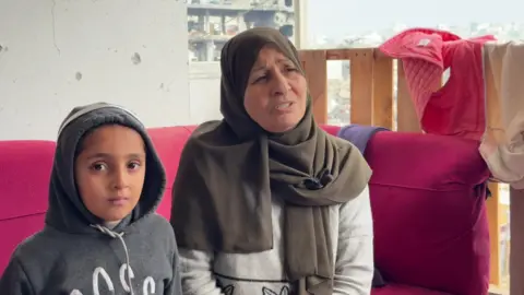 Laila sits on a pink couch with a young girl