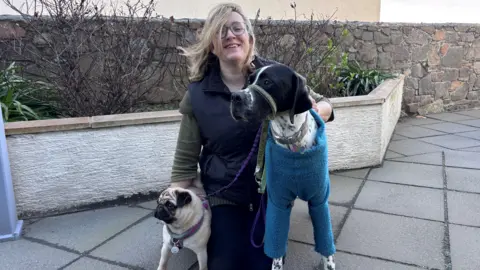 Lynn Symphorien knelt down next to her two dogs Macy and Rumer. 