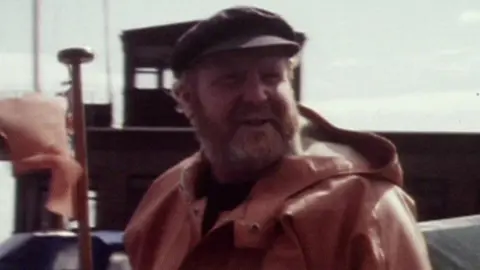 A archive picture of Ray Sedgwick in the ferry with a flag waving alongside him