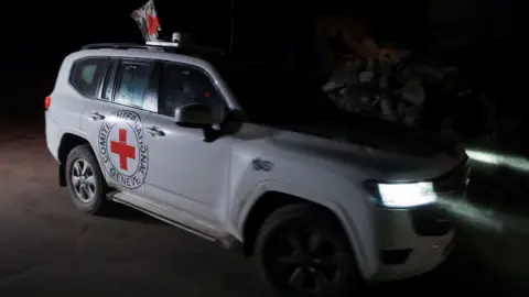 Reuters A white Red Cross jeep with the emblem of a red cross and the organisation's name on the side.
